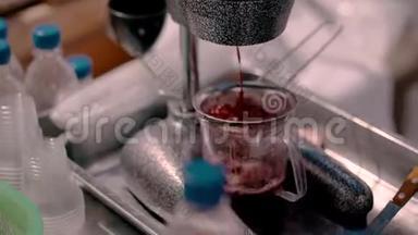 一个戴手套的人用机械榨汁机从水果中榨出果汁。 特写过程。
